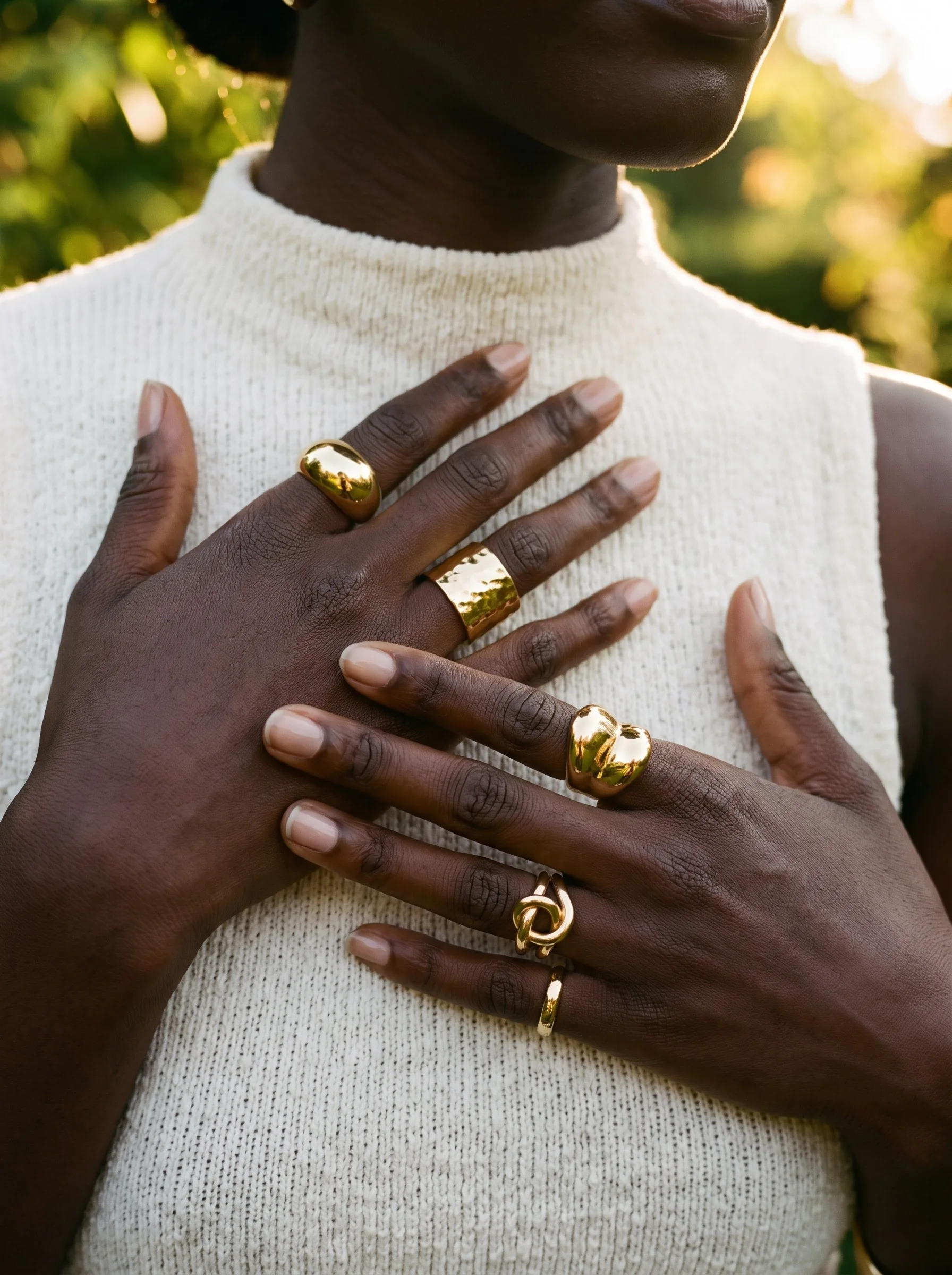 Two hands wearing gold statement rings